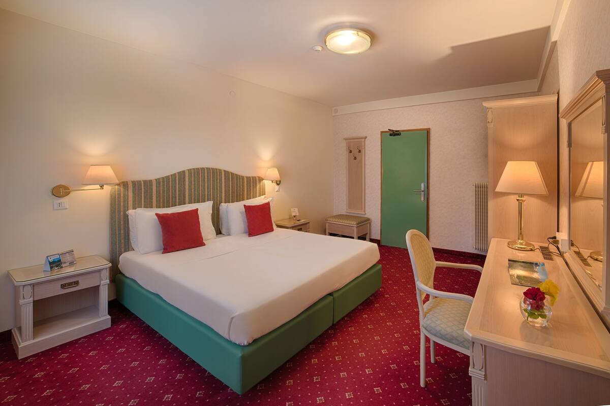 Ein Hotelzimmer mit einem Bett, Nachttischen, einem Schreibtisch und einem Sessel.