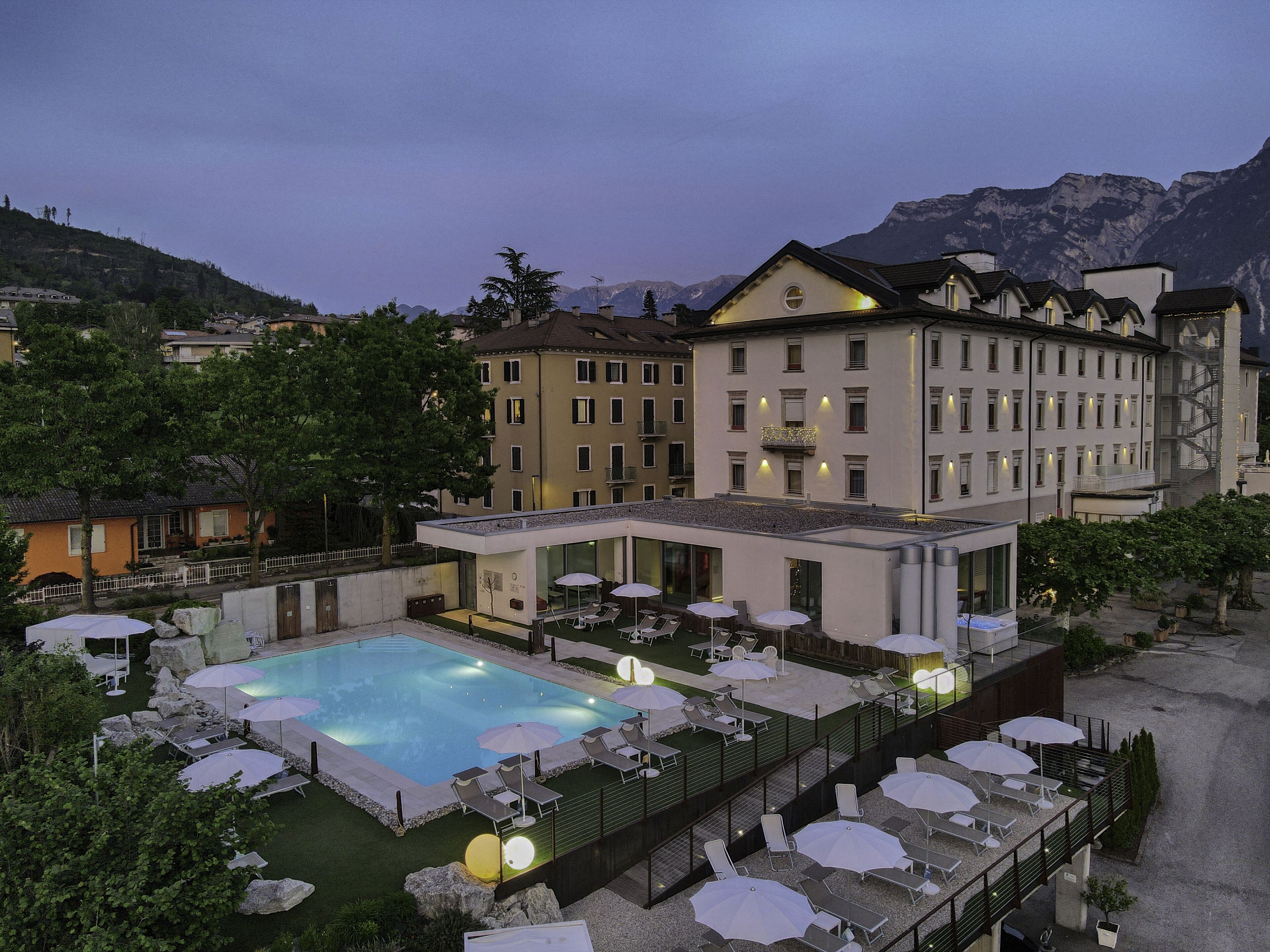 A hotel with a swimming pool, outdoor seating, and mountain views.