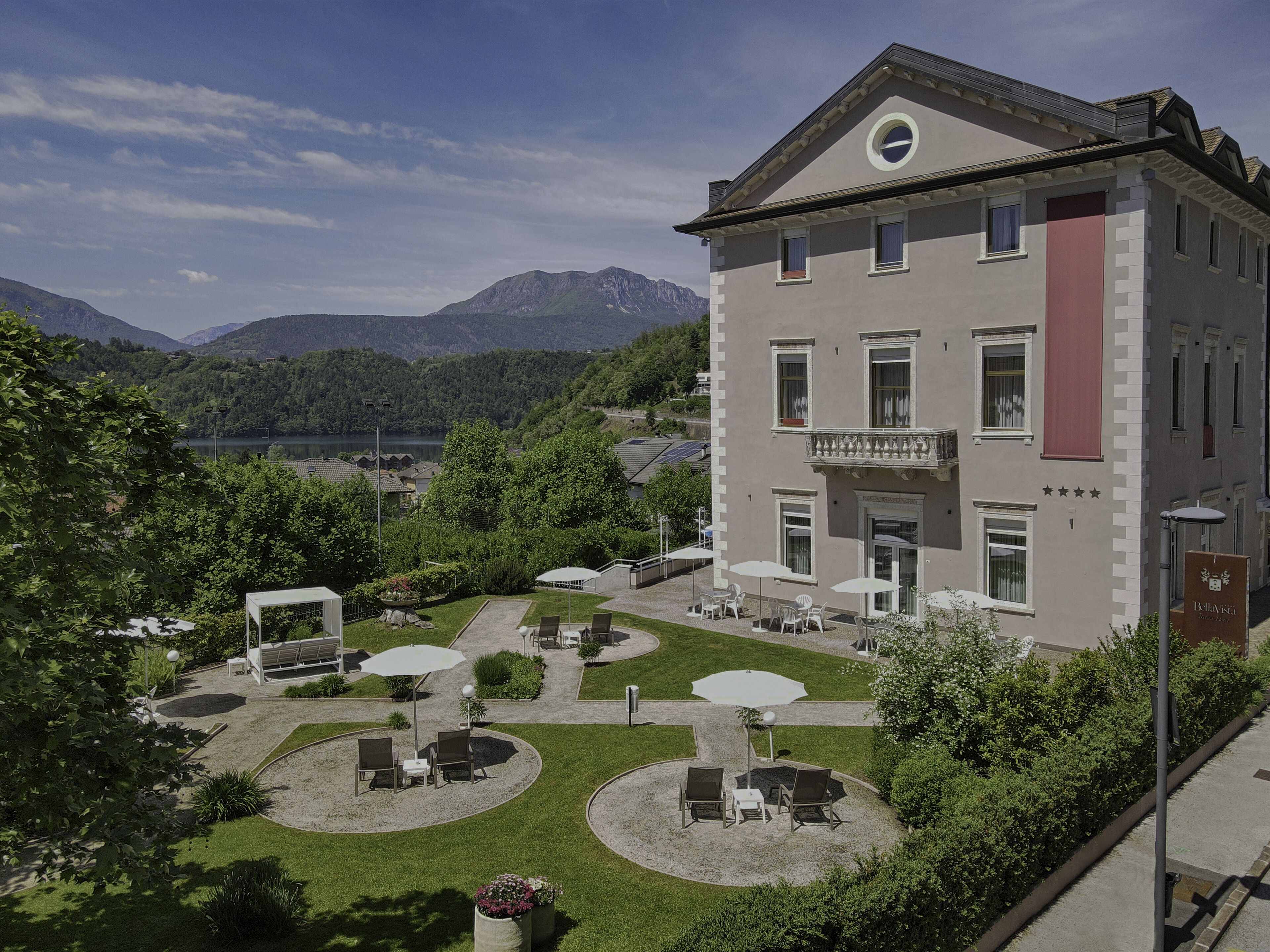 Un hôtel doté d’une cour intérieure avec des espaces de détente en plein air, entourée d’une végétation luxuriante et offrant une vue sur les montagnes.