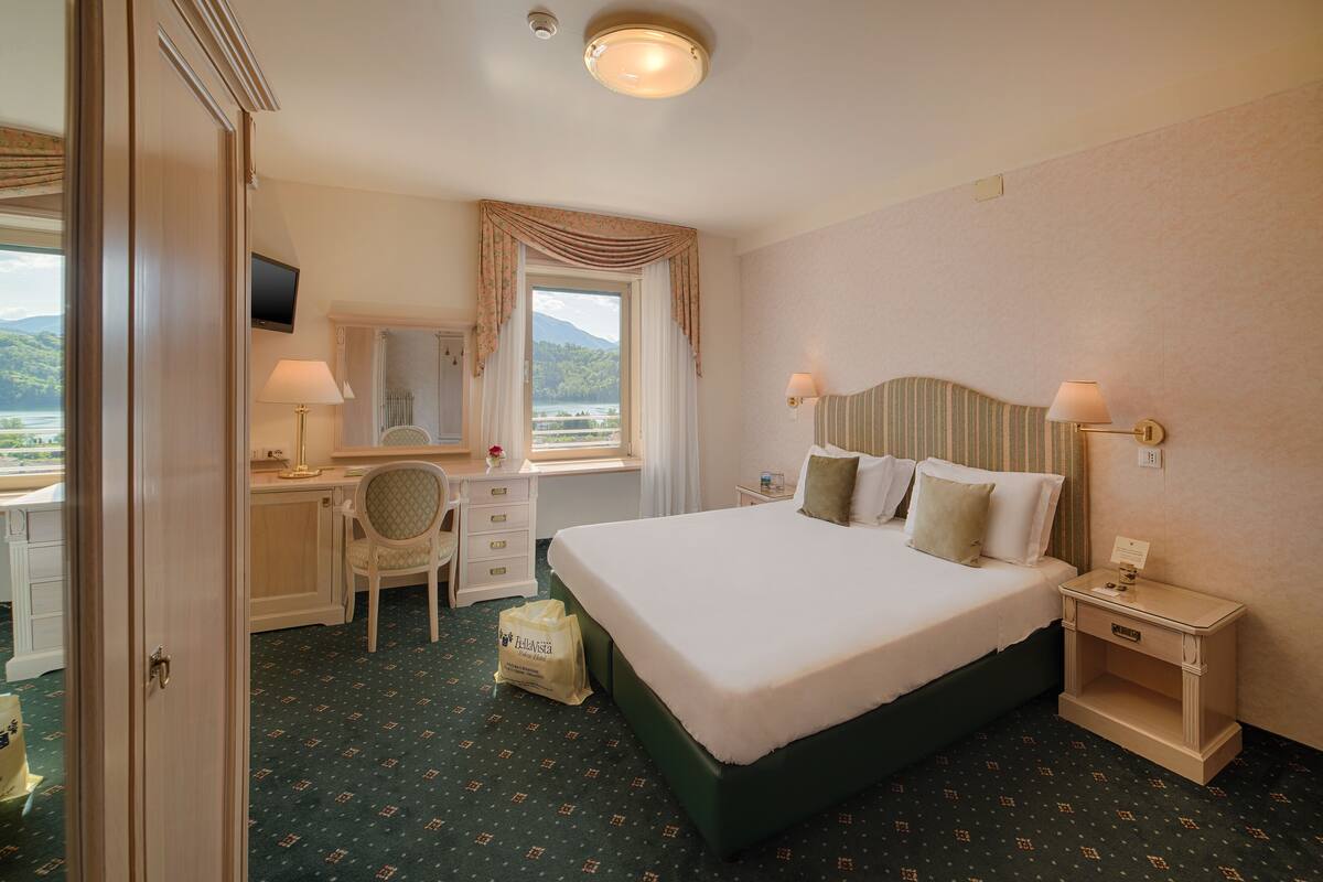 Ein Hotelzimmer mit Bett, Schreibtisch, Stuhl und Blick ins Freie.