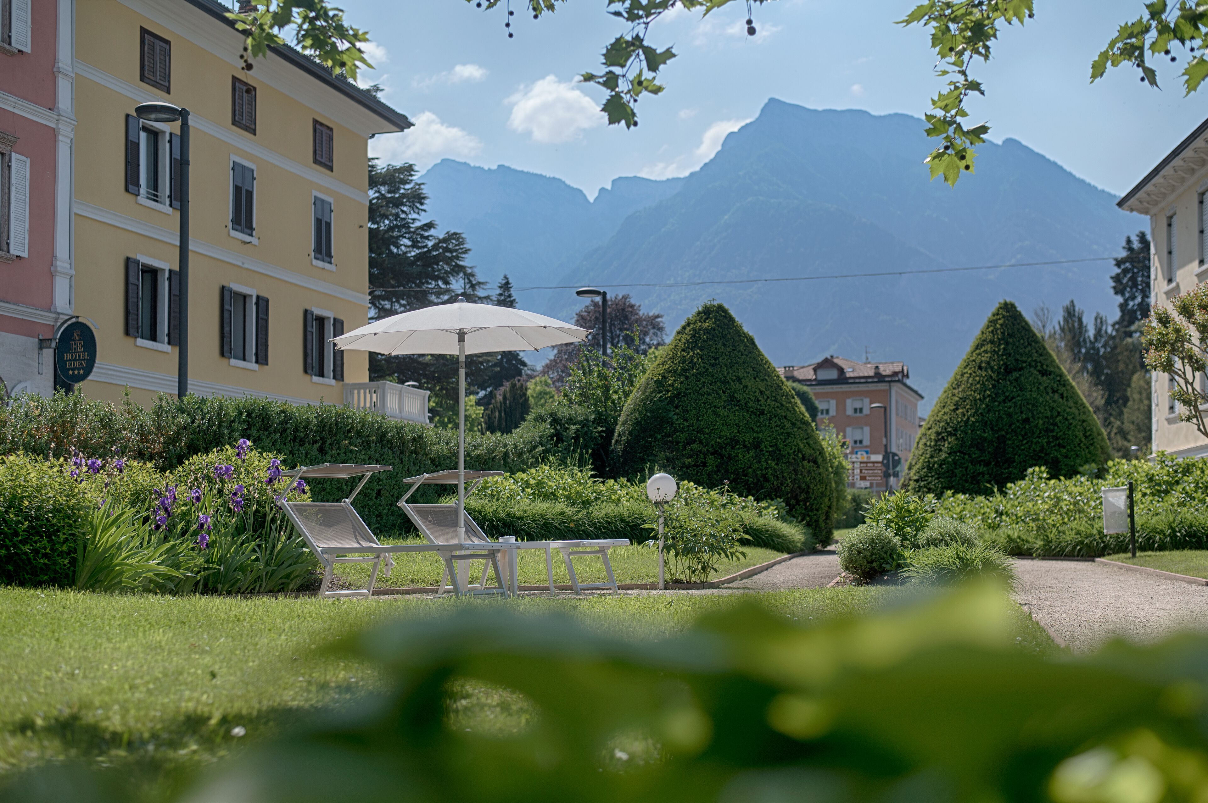 A hotel with a garden, outdoor seating, and mountain views.