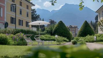 A hotel with a garden, outdoor seating, and mountain views.