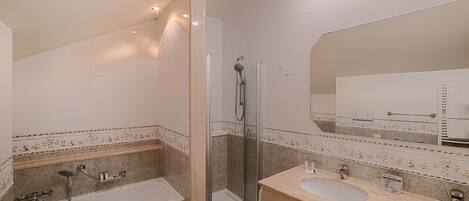 A modern bathroom with a shower, two sinks, and a large mirror.