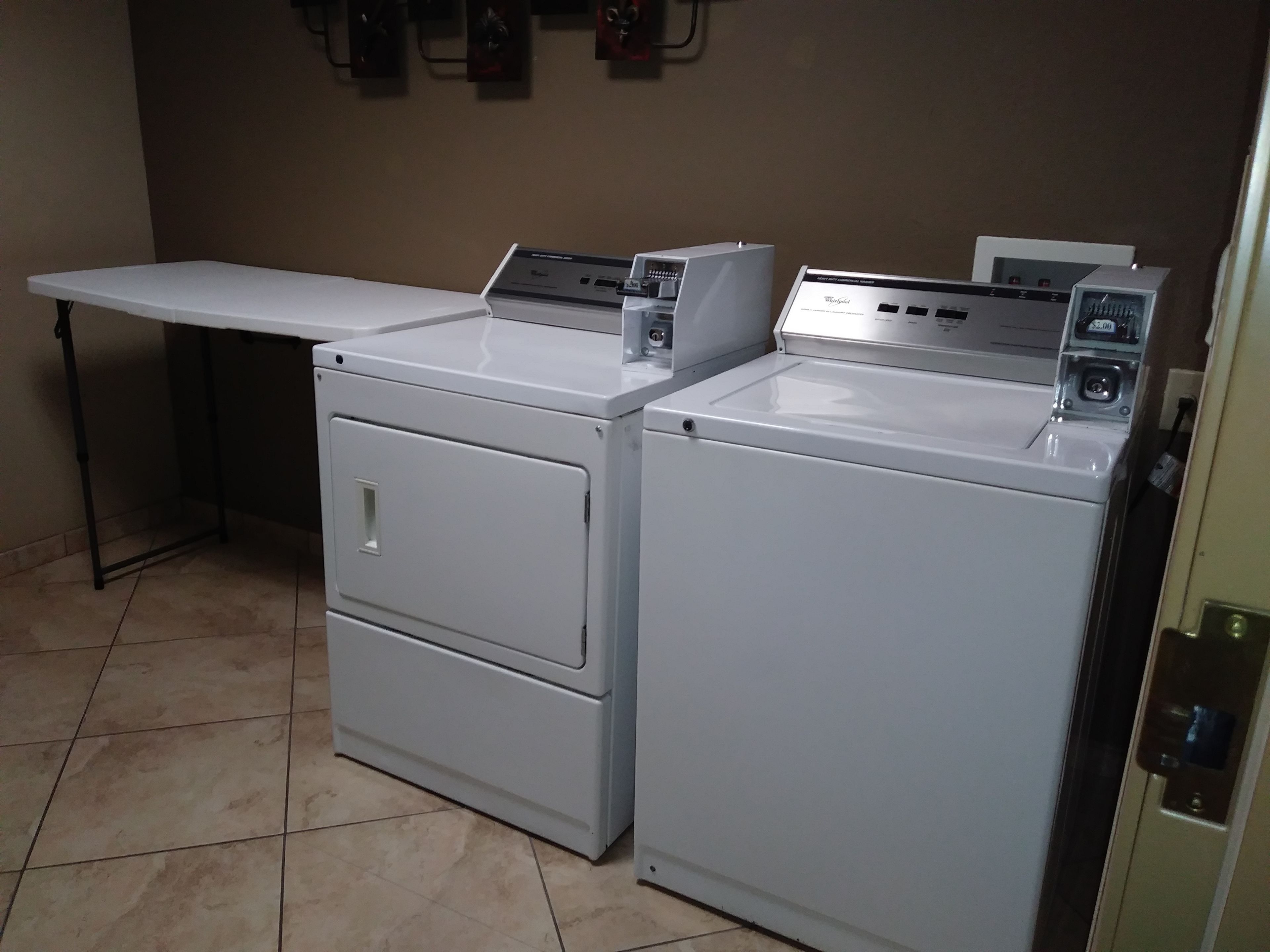 A laundry room with two front-loading washing machines and a table.