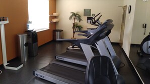 A gym with treadmills, a water dispenser, and a trash can. - Seffner Inn and Suites (Seffner)