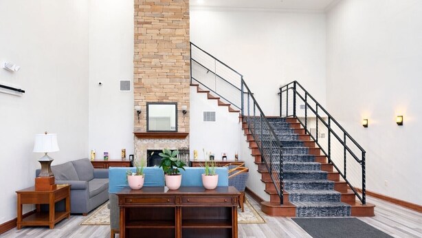 A spacious living room with a fireplace, a staircase, and a dining area. - Seffner Inn and Suites (Seffner)