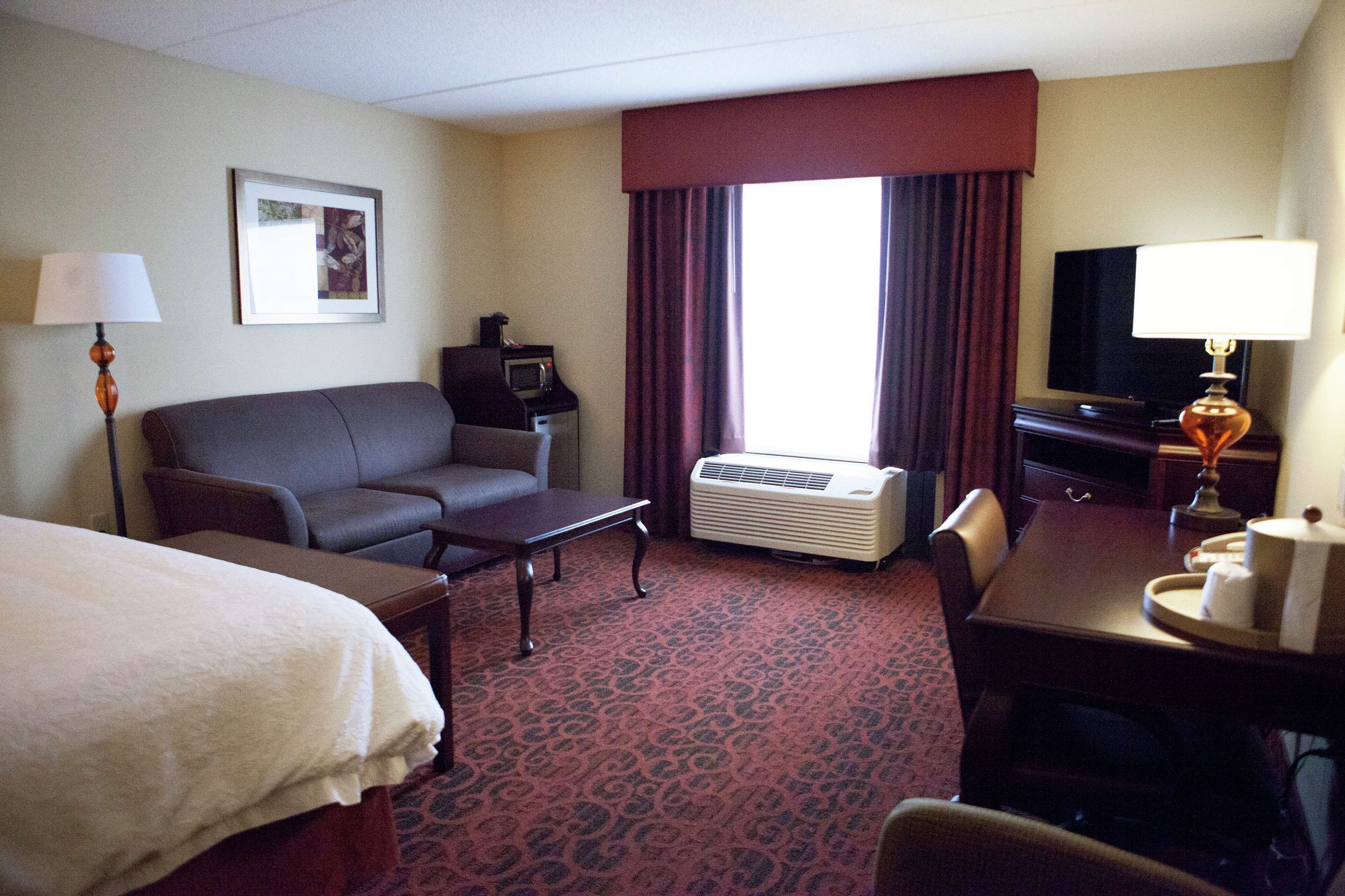 Una habitación de hotel con una cama, un sofá, un escritorio, un televisor y un microondas.