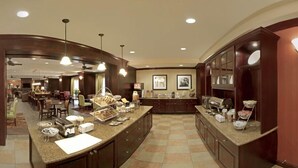 A hotel kitchen with a buffet setup, including a bread display and various food items.