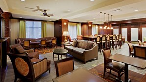 A hotel lobby with a seating area, a reception desk, and a dining area. - Hampton Inn Rochester Webster (Webster)