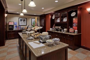 A hotel kitchen with a buffet setup, including a variety of food items and a coffee station. - Hampton Inn Rochester Webster (Webster)