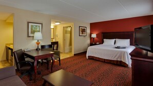 A hotel room with a bed, desk, chair, and TV.