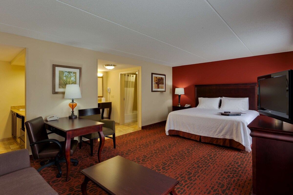 A hotel room with a bed, desk, chair, and TV.