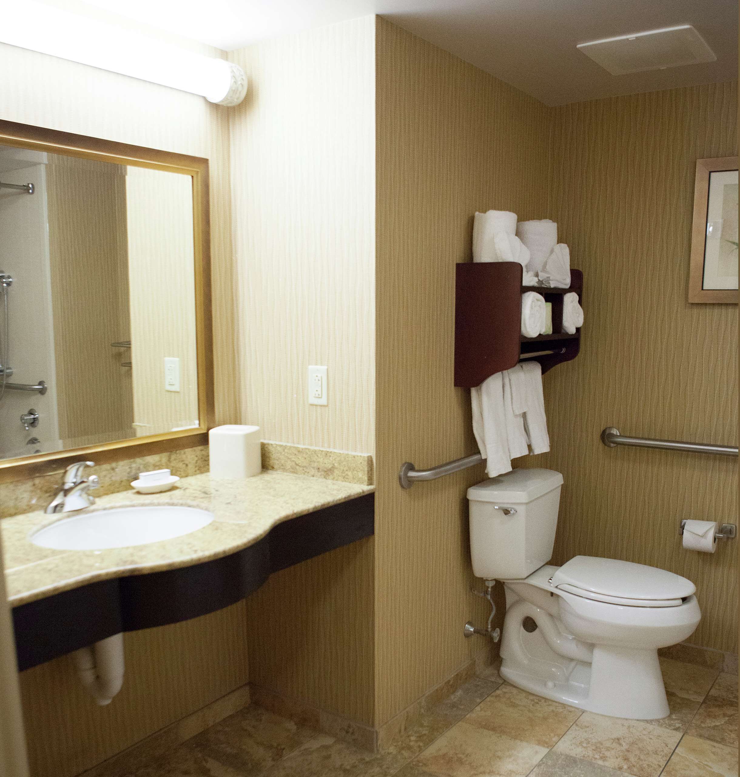 A hotel bathroom with a sink, toilet, and towel rack.