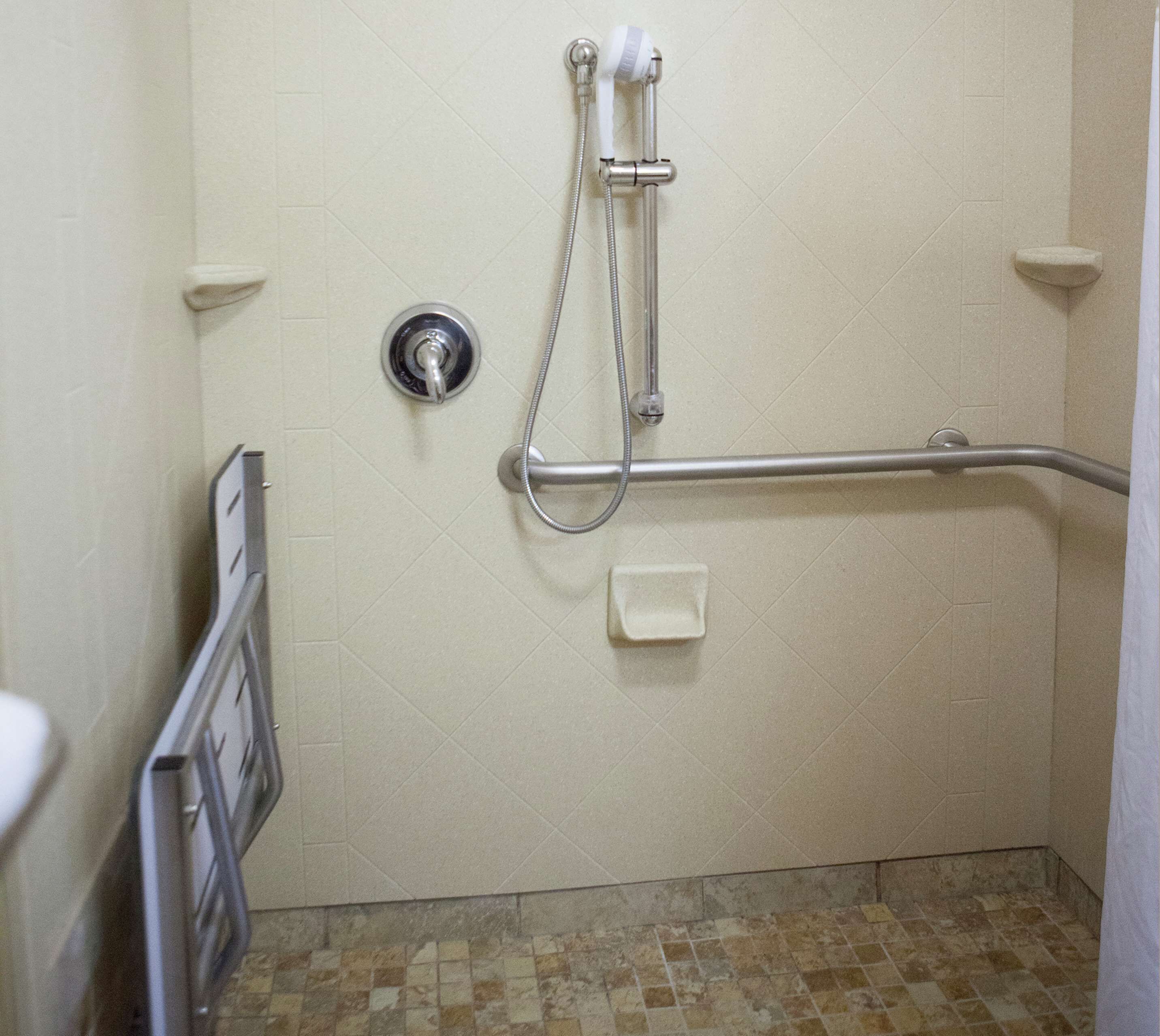 A bathroom with a shower, grab bar, and a toilet.