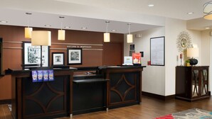 A reception desk with a "Welcome to Matteson" sign, framed pictures, and a decorative mirror. - Hampton Inn & Suites Chicago Southland-Matteson (Matteson)