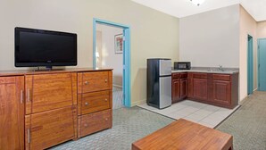 Eine kompakte Küche mit Holzausstattung, inklusive Kühlschrank, Mikrowelle und einem Flachbildfernseher auf einer Holzkommode.