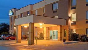 Ein Days Inn Hotel mit überdachtem Eingang, Ziegelbau und einem Parkplatz mit Autos.
