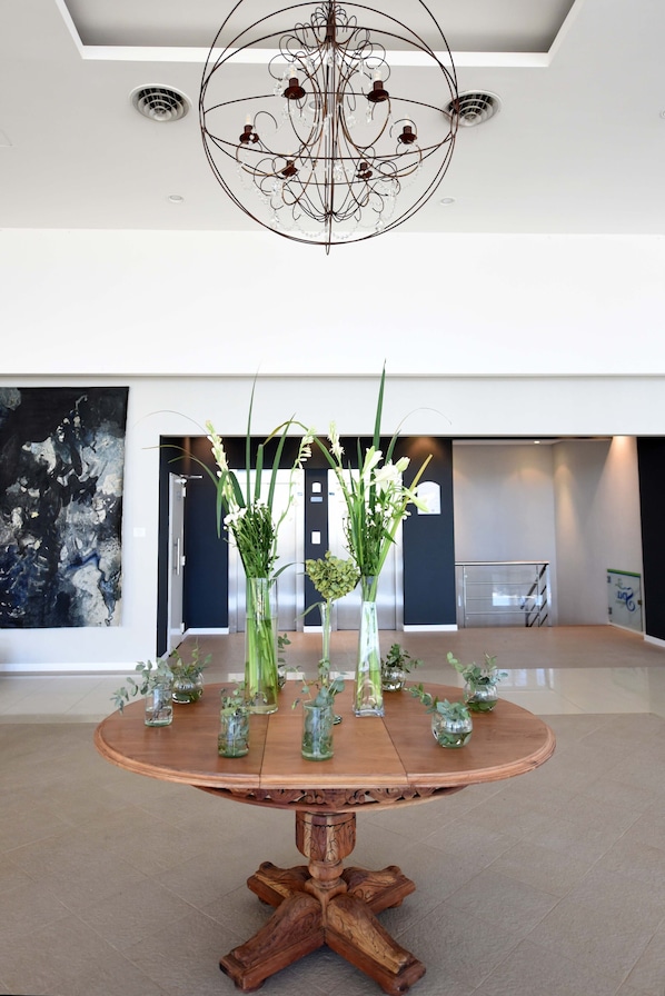 A round wooden table with vases of flowers and a modern chandelier. - Hotel Camberland Ramallo (Ramallo)