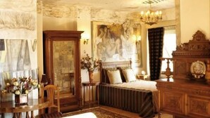 Una habitación con un techo grande y ornamentado, un candelabro, un sofá y una chimenea.