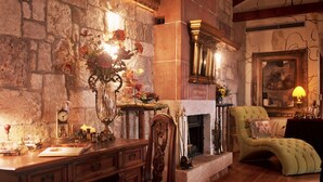 Una habitación acogedora con chimenea de piedra, un escritorio de madera con un florero y un sillón cómodo.