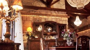 Un rincón comedor acogedor con una mesa y sillas de madera, una araña y un fondo de pared de piedra.