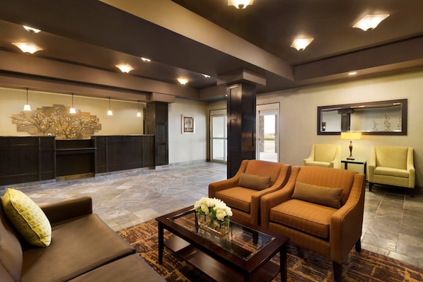 A lobby with a reception desk, two sofas, a coffee table with flowers, and a mirror on the wall.