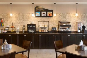 A café with a tiled backsplash, a coffee machine, a display case with pastries, and a sign above the counter. - Days Inn by Wyndham Innisfail (Innisfail)