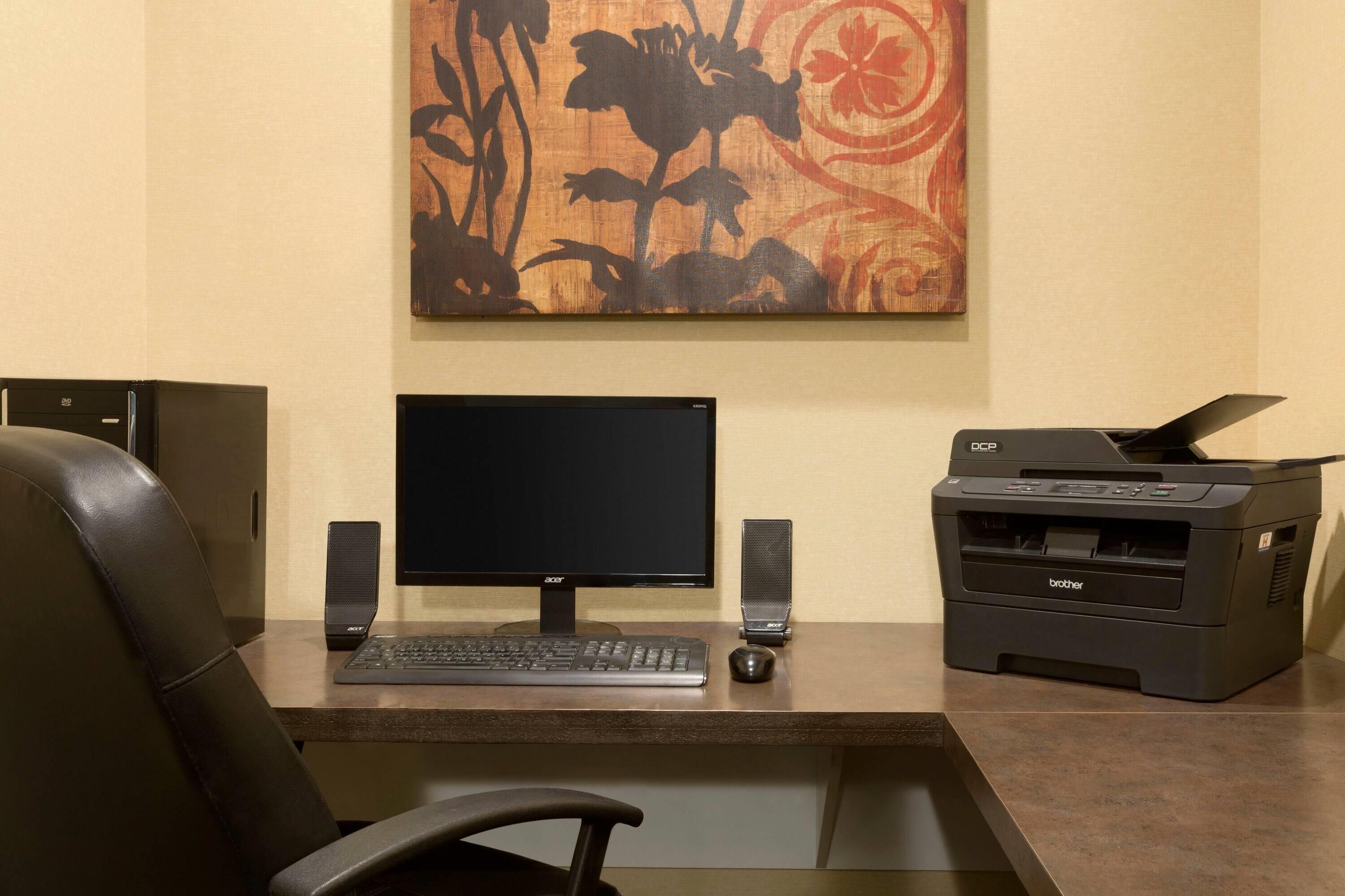 A desk with a computer monitor, keyboard, mouse, and printer.