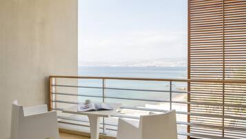 Varanda com mesa e cadeiras, vista para o litoral e guarda-corpo.
