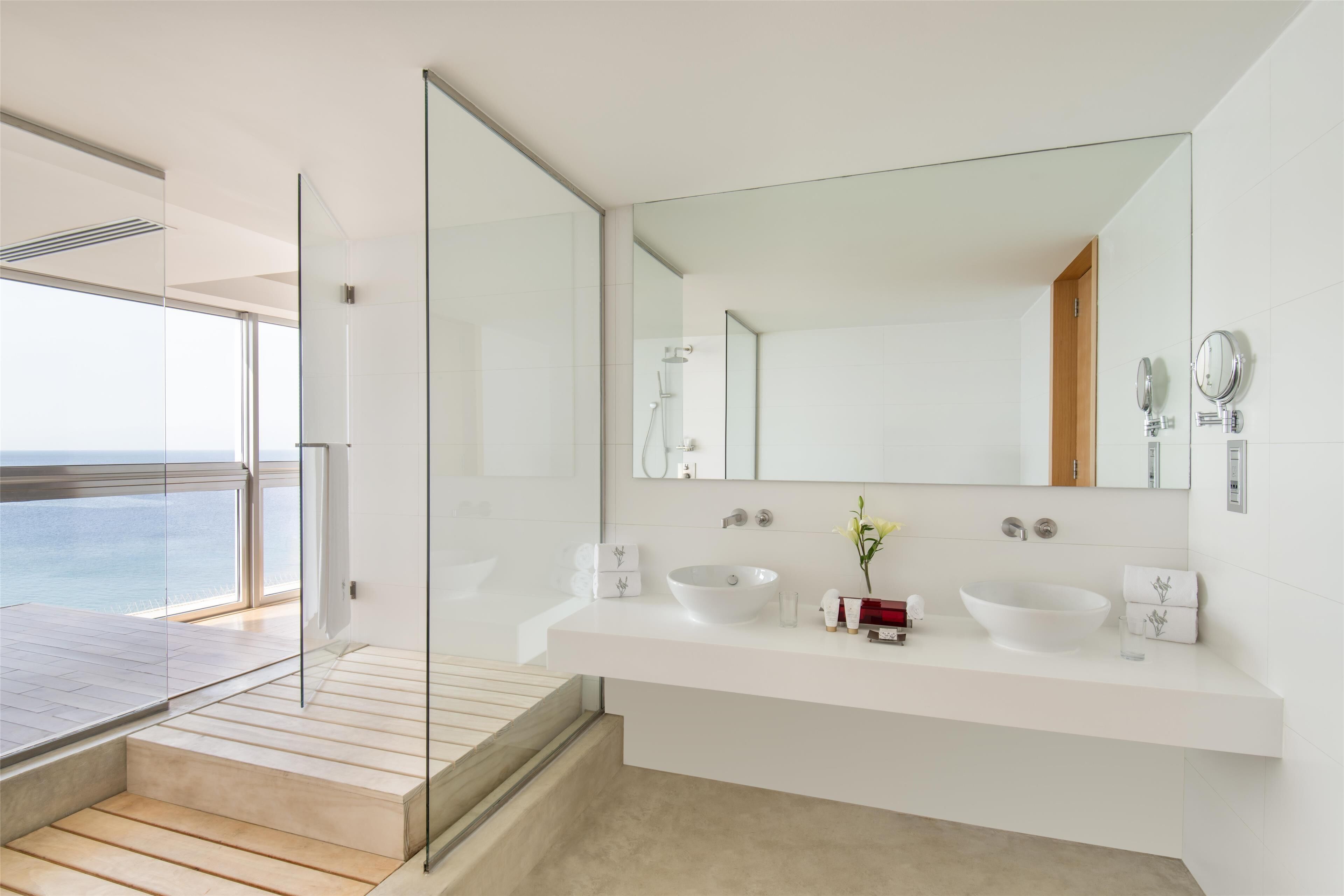 Un bagno moderno con uno specchio grande, due lavandini e una doccia.