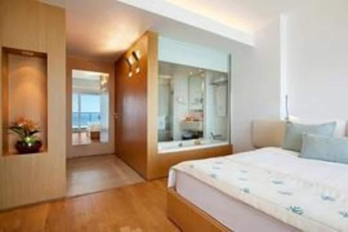 A modern hotel room with a large bed, a walk-in closet, and a view of the city.