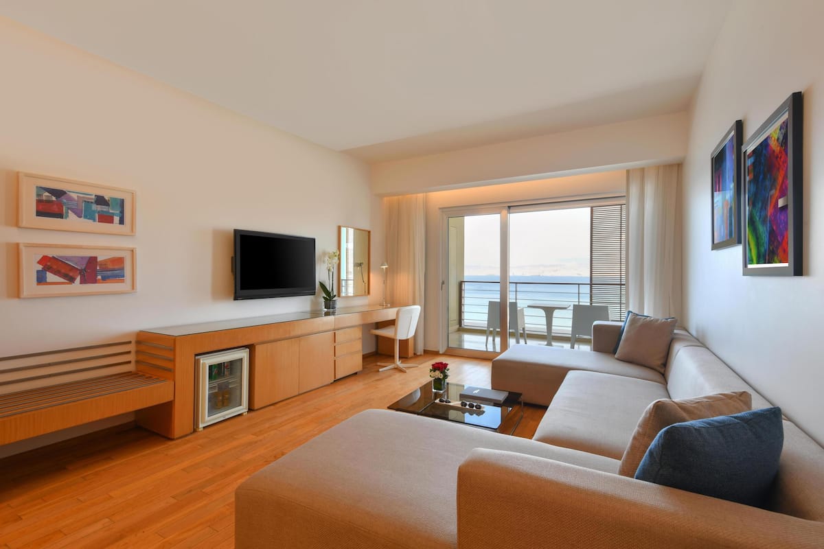 A modern living room with a flat-screen TV, a sofa, a coffee table, and artwork on the walls.