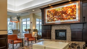 A lobby with a fireplace, seating area, and a large framed artwork. - Hilton Garden Inn St. Louis Airport (St. Louis)