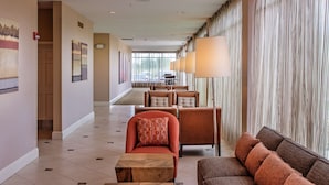 A hotel lobby with a seating area, a reception desk, and a large window with curtains. - Hilton Garden Inn St. Louis Airport (St. Louis)