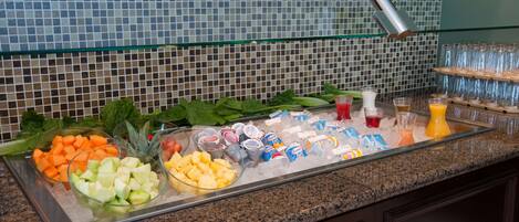 A buffet with various fruits, vegetables, and beverages.