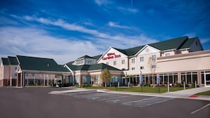 A hotel with a clear sky, parking lot, and a sign for the Hilton Garden Inn. - Hilton Garden Inn St. Louis Airport (St. Louis)