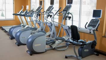 A row of PRECOR elliptical machines in a gym with large windows and orange walls.