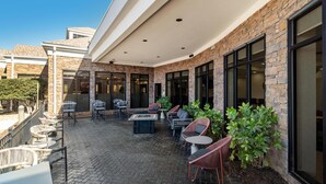 A covered patio with outdoor seating, a fire pit, and a view of the building's interior. - Hilton Garden Inn Cartersville (Cartersville)