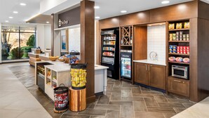 A self-service kiosk area with chilled and frozen food sections, a microwave, and a trash bin. - Hilton Garden Inn Cartersville (Cartersville)
