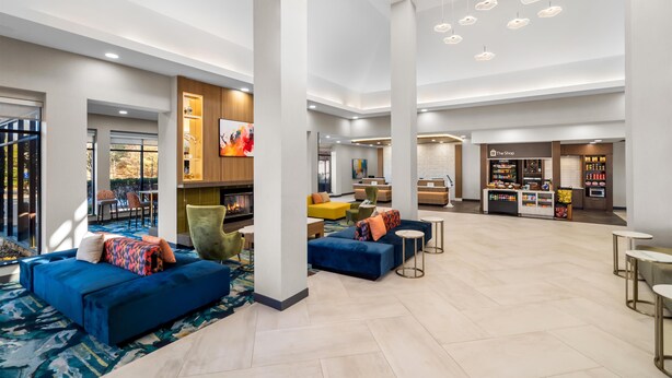 A spacious lobby with a high ceiling, seating areas, a fireplace, and a shop named "The Shop". - Hilton Garden Inn Cartersville (Cartersville)