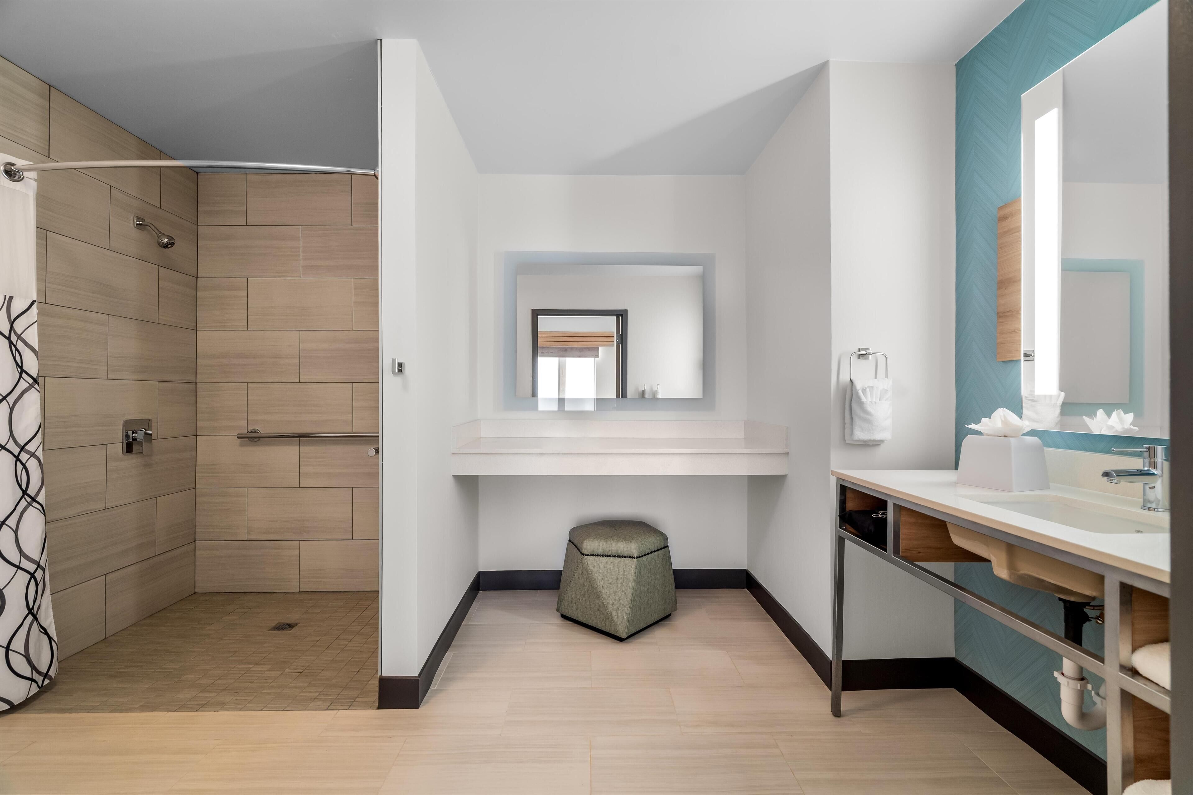 A modern bathroom with a shower, a vanity with a mirror, and a toilet.