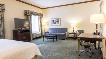 A hotel room with a bed, a desk, a sofa, a TV, and two lamps.