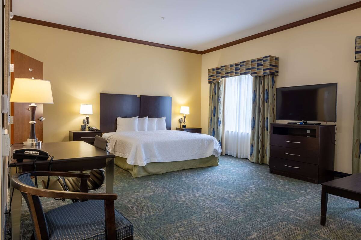 Une chambre d’hôtel comprenant un lit, un bureau avec un téléphone, une chaise, une télévision et une commode.