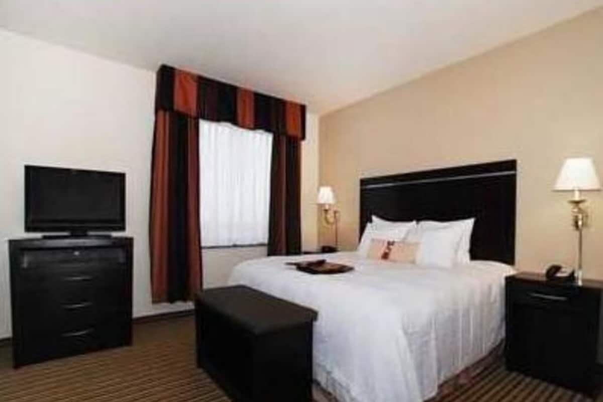 A hotel room with a bed, a TV, a desk, and a lamp.