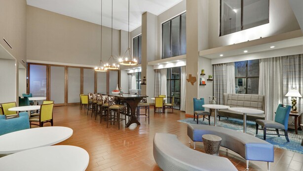 Een ruime hotellobby met een eetgedeelte, zitjes en grote ramen.