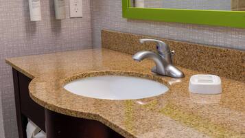 Un baño con encimera de granito, grifo plateado y lavabo blanco.