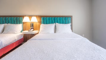 Une chambre d’hôtel avec deux lits, une table de chevet avec une lampe et une tête de lit en bois.