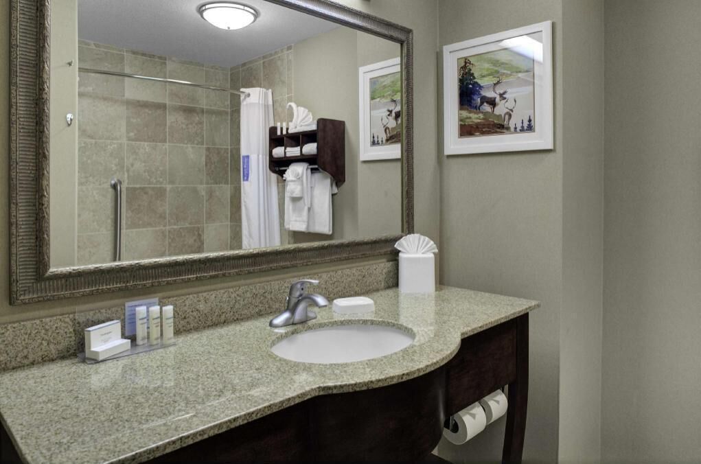 A bathroom with a granite countertop, a sink, a mirror, a towel rack, and two framed pictures on the wall.