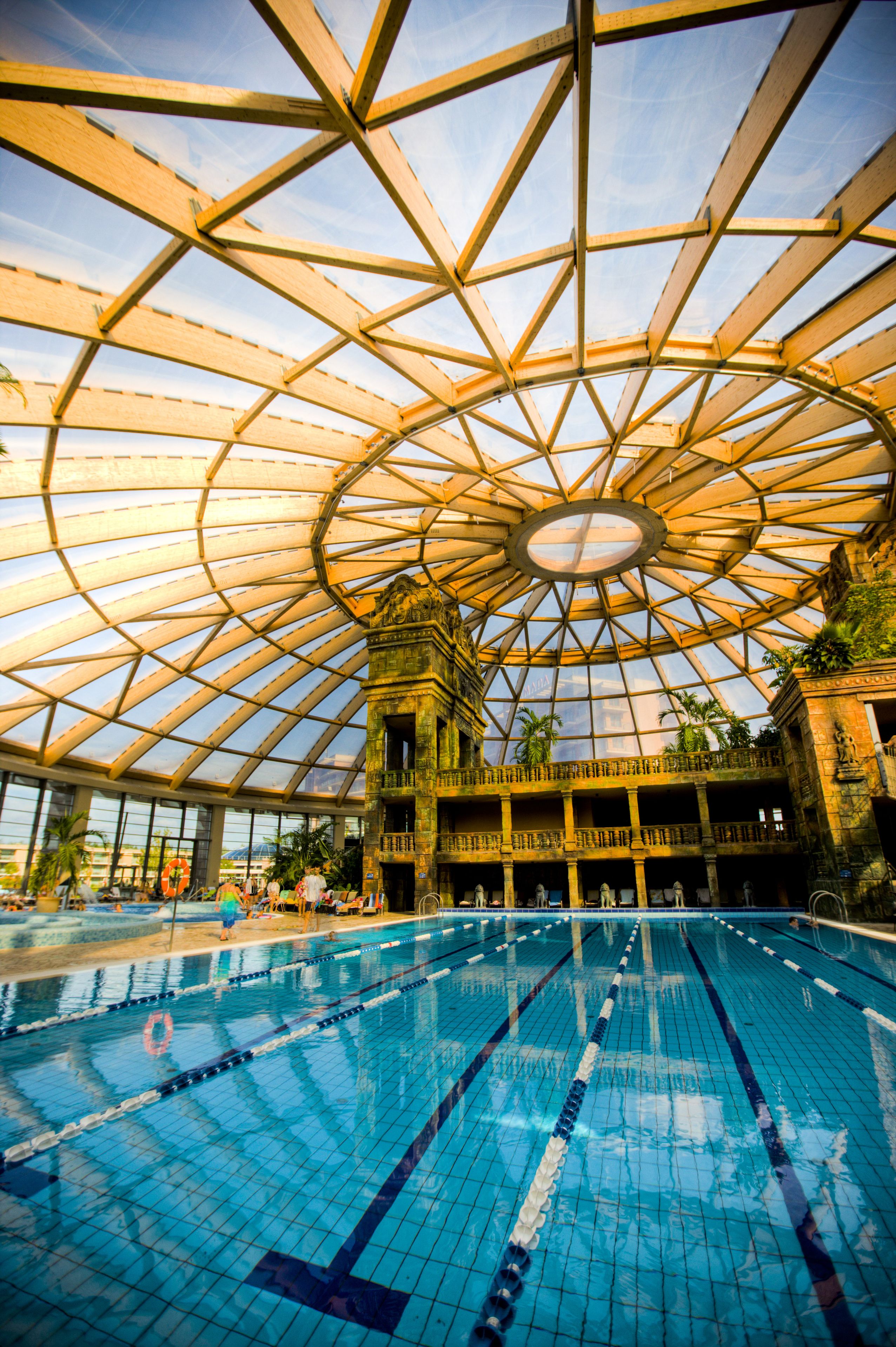 A large indoor swimming pool with a glass ceiling and multiple levels of balconies.