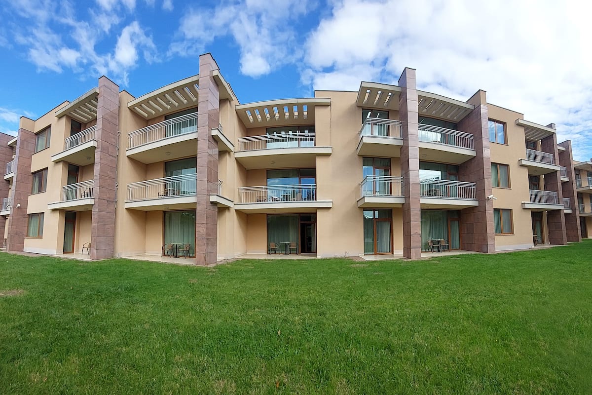 A multi-story residential building with balconies, large windows, and a flat roof.